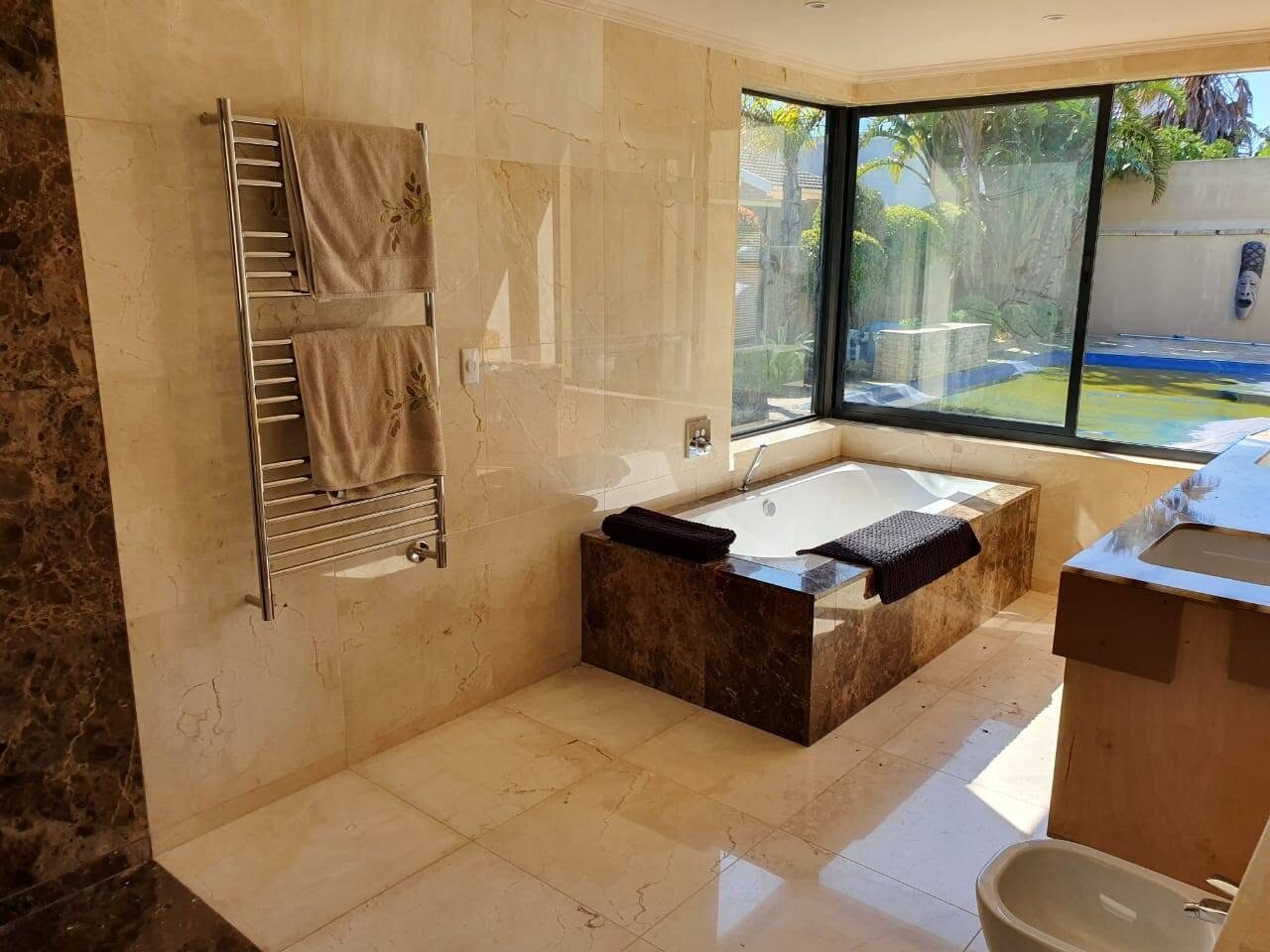 Tiled bathroom project with built-in bath, towel rail, large windows, and vanity